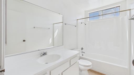 A white bathroom with a toilet, sink, and shower.