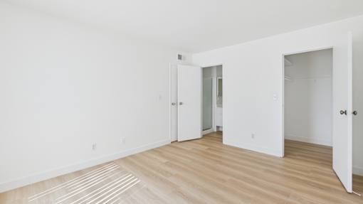 A room with white walls and wooden flooring with two doors.