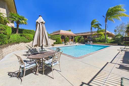 A patio with a table and chairs is set up next to a pool.