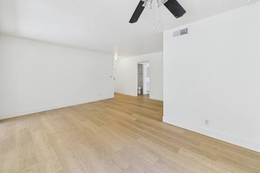 A room with a ceiling fan and wooden flooring.