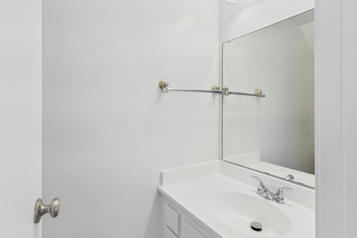 A white bathroom with a sink and mirror.