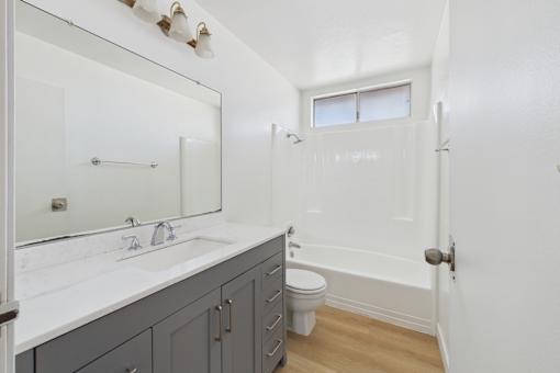 A white bathroom with a toilet, sink, and bathtub.