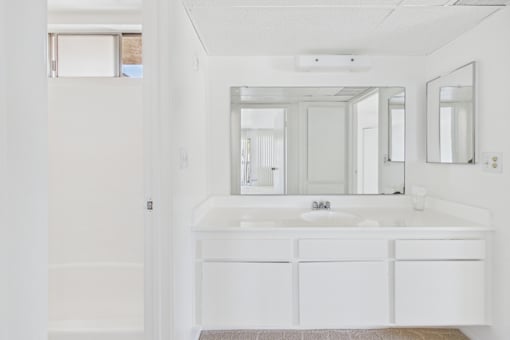 A white bathroom with a sink and mirrors.