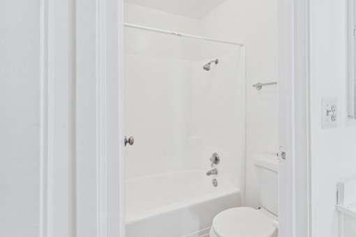 A white bathroom with a toilet, sink, and bathtub.