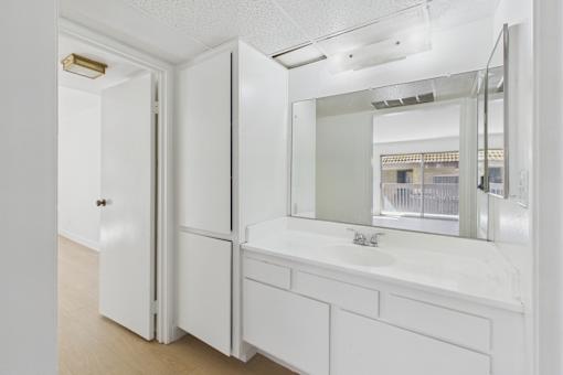 A white bathroom with a sink and mirror.