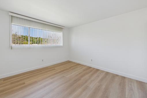 A room with wooden flooring and a window with blinds.
