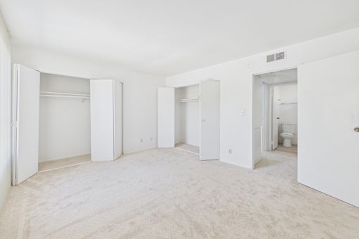 A large, empty room with white walls and carpeting.