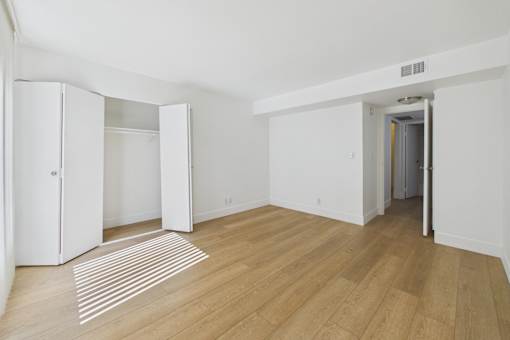 A room with white walls and wooden flooring with a striped rug.
