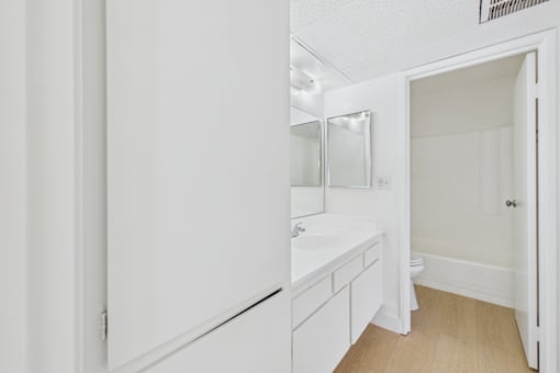 A white bathroom with a sink and mirror.