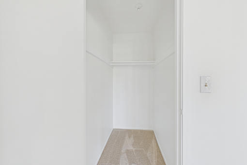A small room with a carpet and a light switch on the wall.