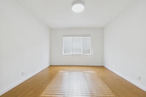 A room with wooden floors and a window with blinds.