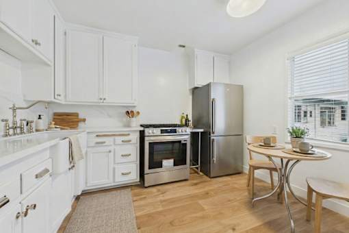 A kitchen with white cabinets and a stainless steel refrigerator.
