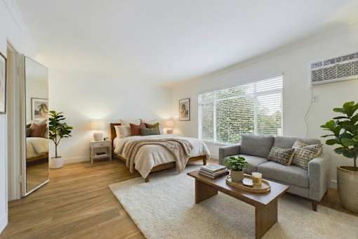 A well-lit bedroom with a large bed and a grey sofa.