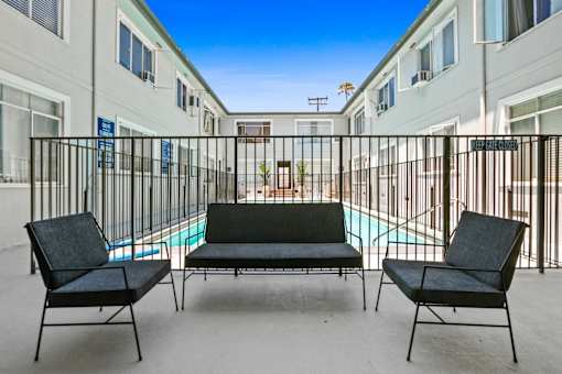 A black chair is in front of a pool in a courtyard.