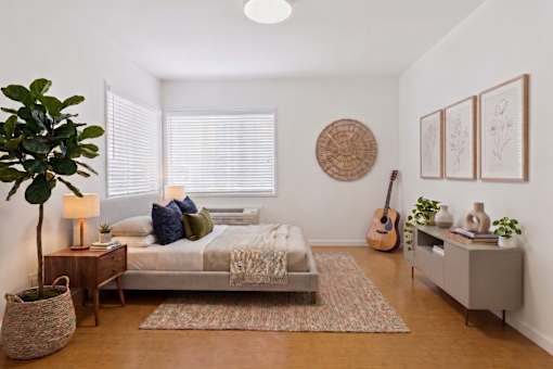 A bedroom with a bed, nightstand, and a guitar on the wall.