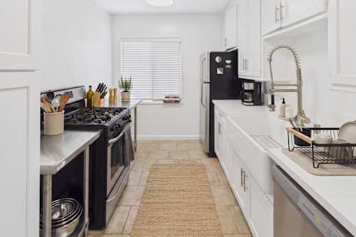 A kitchen with black appliances and white cabinets.