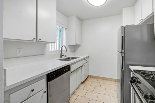 an empty kitchen with white cabinets and stainless steel appliances