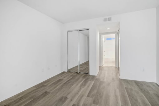 an empty room with white walls and wood floors and a sliding glass door