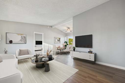 A living room with a white couch, a coffee table, and a flat screen TV.