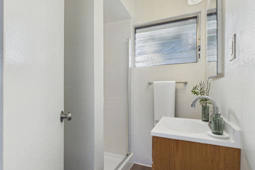A white bathroom with a sink and mirror.