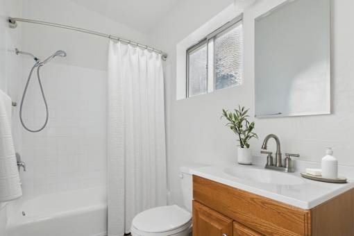 A white bathroom with a toilet, sink, and shower.