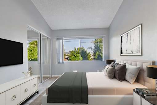 A bedroom with a large bed, a flat screen TV, and a window with a view of trees.
