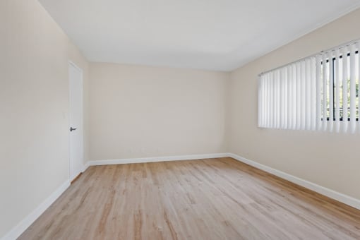 a bedroom with hardwood floors and a large window