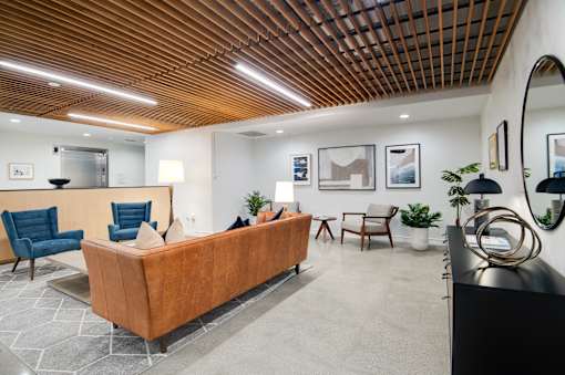 A modern waiting room with a wooden ceiling and a long brown couch.