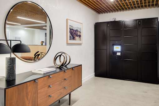 A black and wood dresser with a round mirror above it.