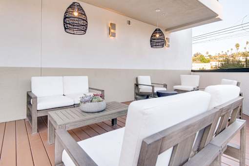 A white couch is on a wooden deck with a table and chairs.
