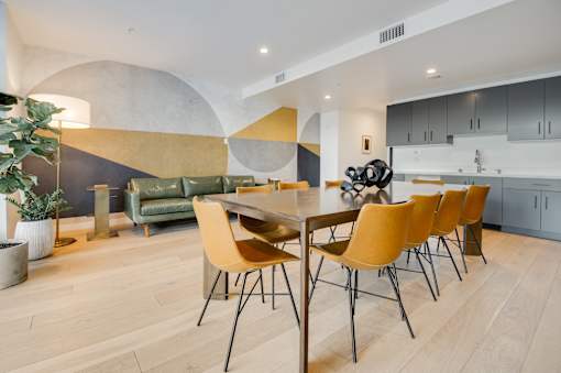 A modern dining room with a wooden table and yellow chairs.