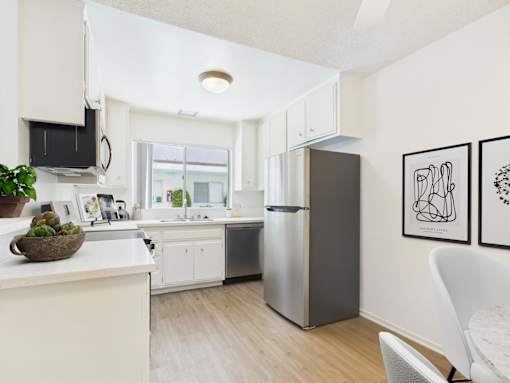A modern kitchen with a refrigerator, sink, and dining table.