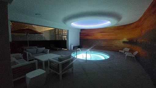 A modern outdoor seating area with a hot tub and a large mural on the wall.
