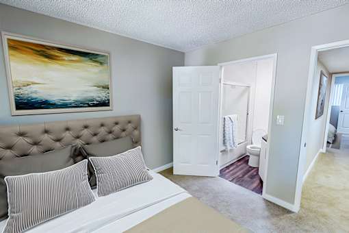 A bedroom with a bed, pillows, and a painting on the wall.