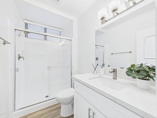 A white bathroom with a toilet, sink, and mirror.