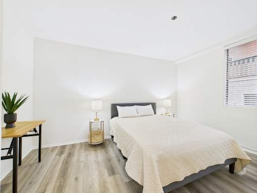 A bedroom with a bed, nightstand, and lamp.