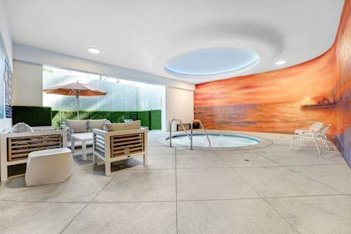 A modern outdoor seating area with a pool and a mural on the wall.