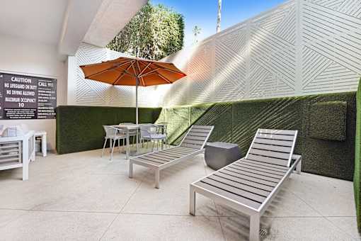 A patio with a table, chairs and a sign.
