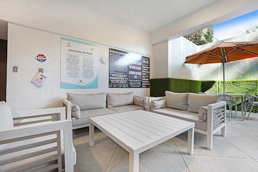 A white patio with a table and chairs and a poster on the wall.