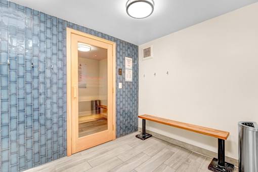 A room with a blue tile wall and a wooden bench.
