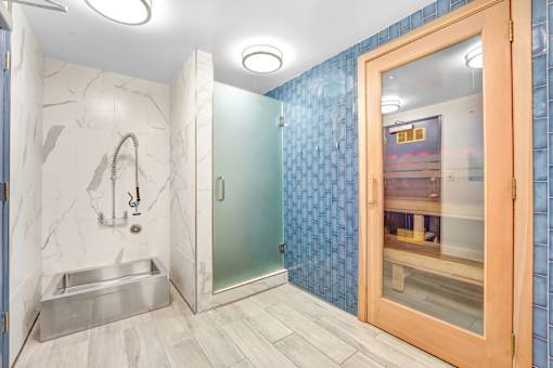 A bathroom with a marble wall and a glass shower door.