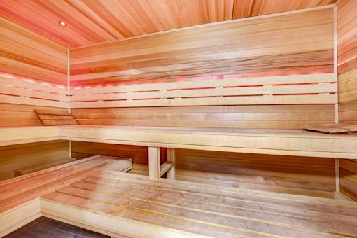 A wooden sauna with benches and a light on the ceiling.