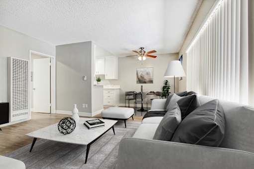 A modern living room with a grey couch, a white coffee table, and a ceiling fan.
