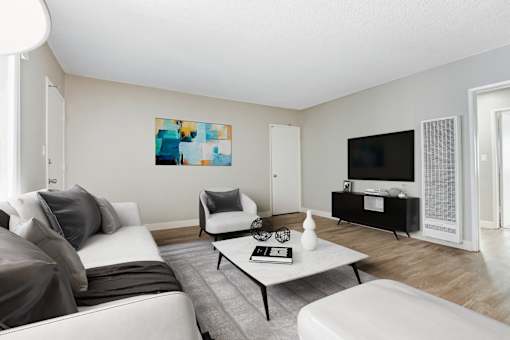 A living room with a grey couch, a white armchair, a coffee table, and a painting on the wall.
