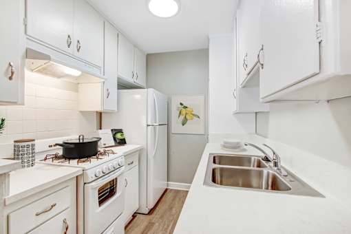 A white kitchen with a stove, sink, and refrigerator.