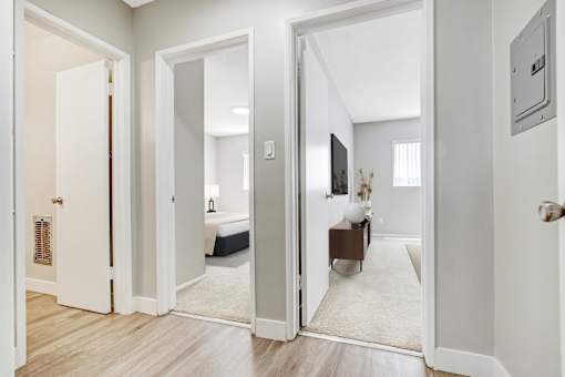 A hallway with a white door and a mirror on the wall.