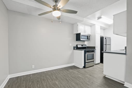 the spacious living room and kitchen with stainless steel appliances and a ceiling fan