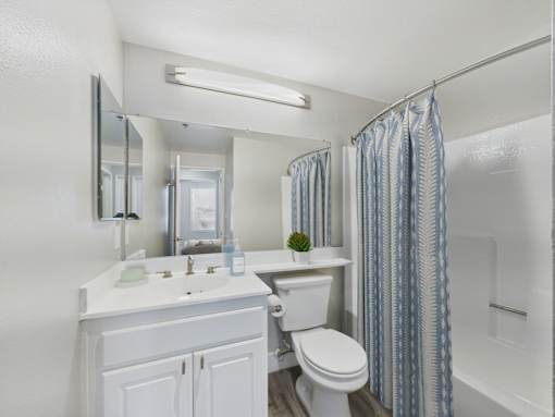 A white bathroom with a sink, toilet, and shower.