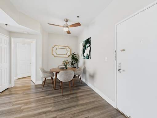 A dining room with a table set for two and a ceiling fan.