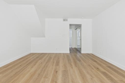 A room with wooden flooring and white walls.